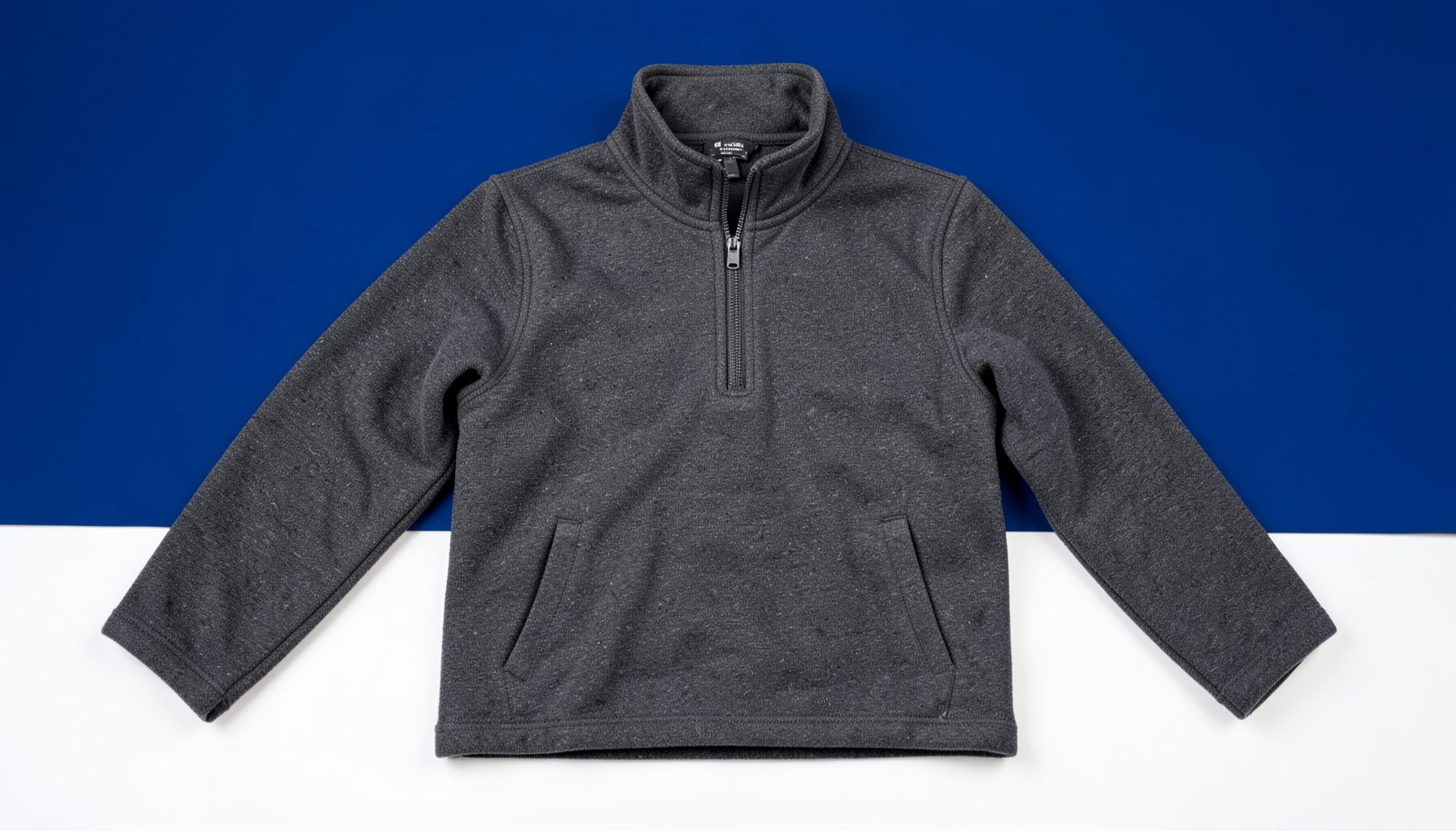A dark grey technical fleece mid-layer with a half-zip front, photographed flat on a clean white surface